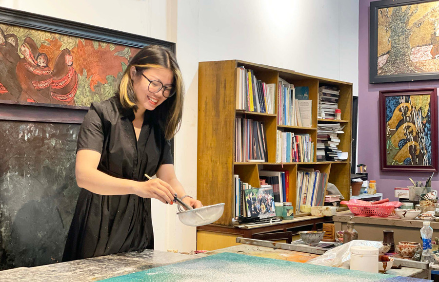 Họa sĩ Mai Thị Kim Uyên thực hiện công đoạn rây bạc lên tranh sơn mài. Ảnh: Phương Duyên