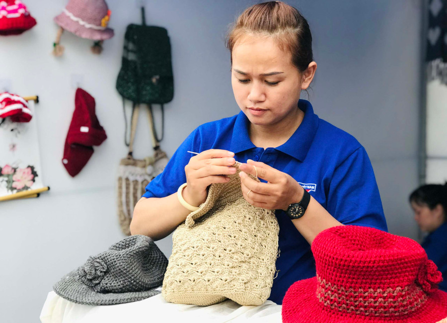 Chị Phạm Thị Hòa đang tỉ mẩn hoàn thành chiếc túi xách. Ảnh: Trần Dung