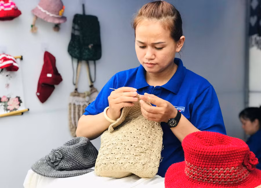 Chị Phạm Thị Hòa đang tỉ mẩn hoàn thành chiếc túi xách. Ảnh: Trần Dung