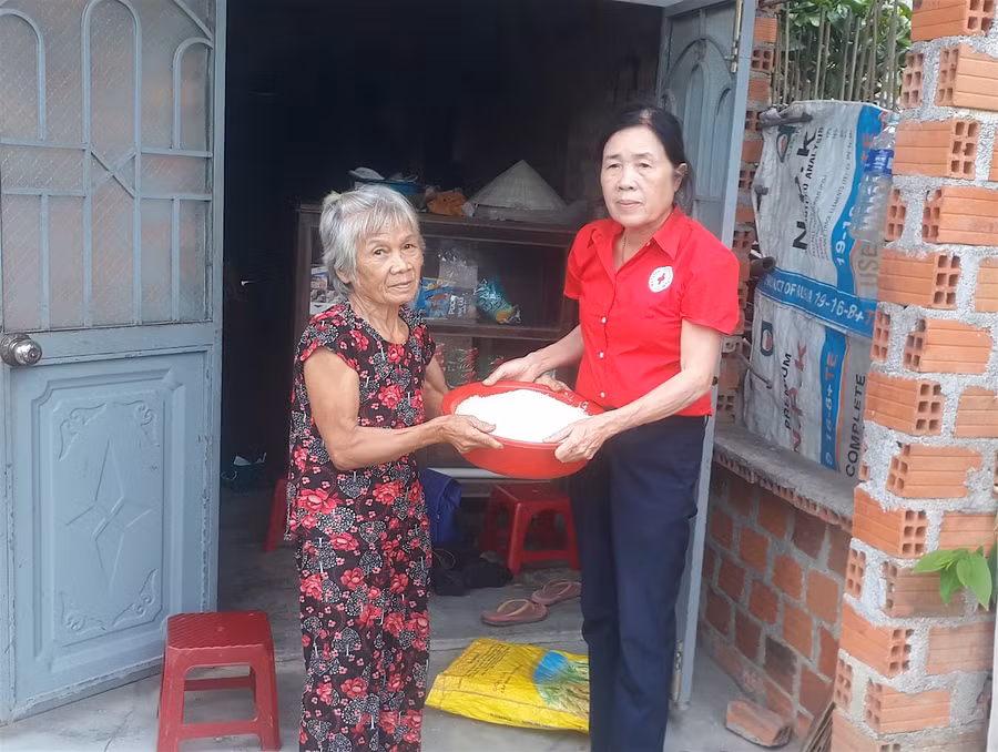 Bà Võ Thị Thanh Hương (bìa trái, thôn Tú Thủy 2, xã Tú An) xúc động nhận phần gạo hỗ trợ từ Chủ tịch Hội Chữ thập đỏ xã Nguyễn Thị Hồng Thu. Ảnh: Mộc Trà