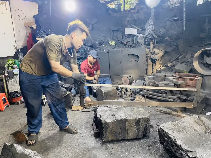 Cậu con rể của vợ chồng anh Quyết đang tập cưa than.