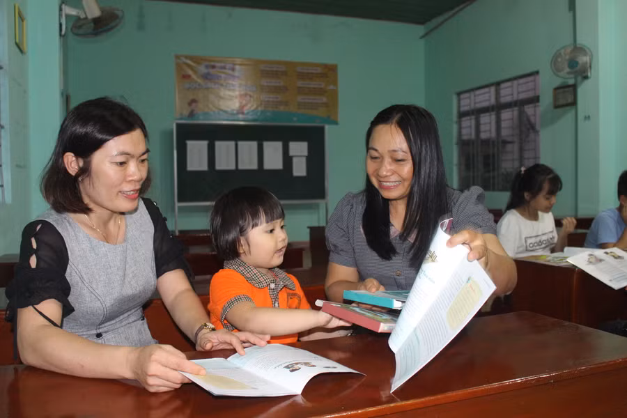 Chị Đinh Thị Phương Chi (bìa phải)-Chủ nhiệm CLB Cùng con đọc sách hướng dẫn phụ huynh và thiếu nhi cách tương tác và đọc sách. Ảnh Minh Nhật