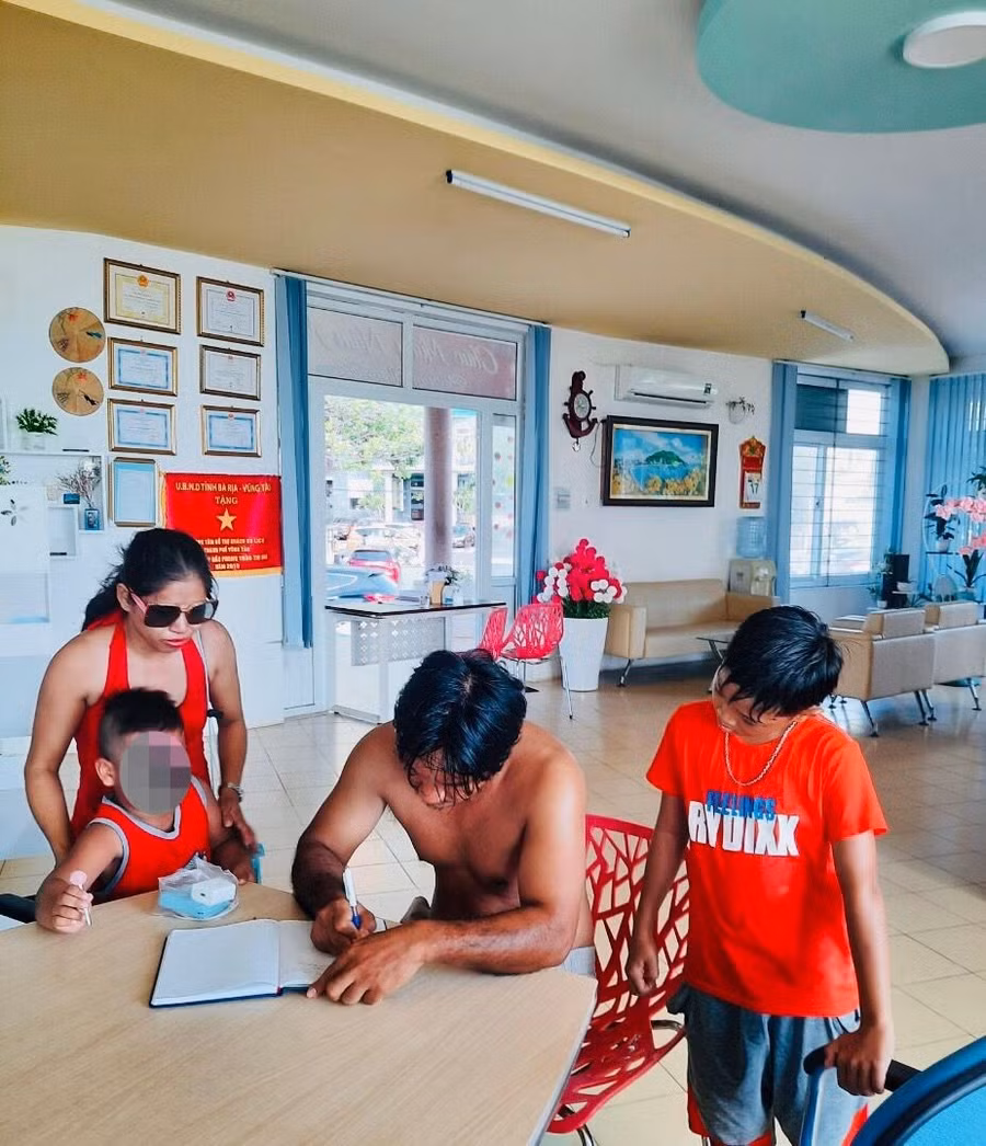  Anh Bùi Nguyên Tuấn (giữa) bàn giao hai bé bị đuối nước vừa được cứu kịp cho gia đình. Ảnh: Lê Vân