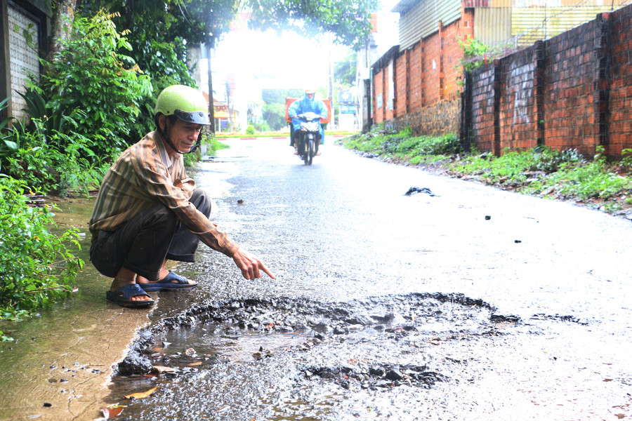Ông Hoàng Xuân Huy chỉ cho P.V những chỗ hư hỏng năng trên đường An Dương Vương. Ảnh: Quang Tấn