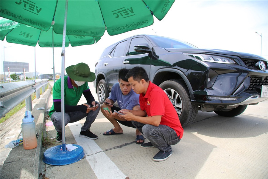 Nhân viên (áo xanh) hướng dẫn cho khách hàng cách thức nạp tiền vào tài khoản để đủ điều kiện lưu thông trên cao tốc. Nhiều khách hàng tỏ ra mệt mỏi khi bị buộc phải dừng lại khi qua trạm thu phí vì chưa dán thẻ ETC.