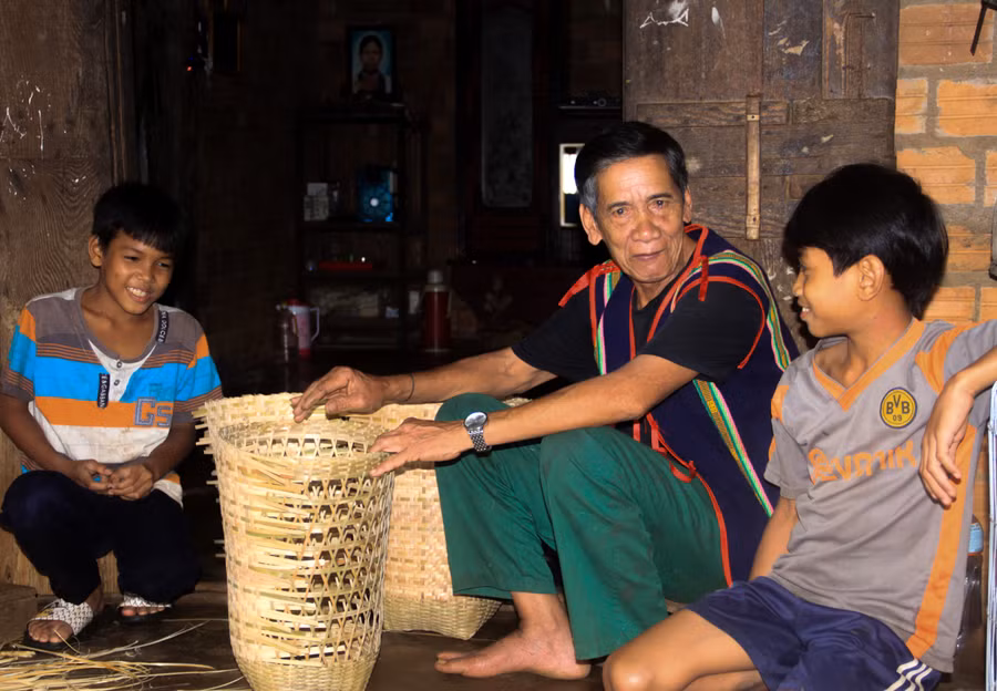 Ông A Dip tranh thủ những lúc đan lát để trò chuyện và dạy dỗ các cháu về văn hóa truyền thống của dân tộc. Ảnh: HT