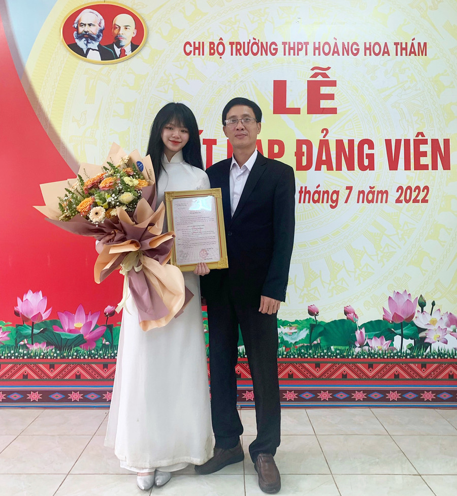  Thầy Nguyễn Văn Tàu-Bí thư chi bộ, Hiệu trưởng Trường THPT Hoàng Hoa Thám tặng hoa chúc mừng đảng viên trẻ Nguyễn Thị Minh Khánh. Ảnh: Thủy Bình
