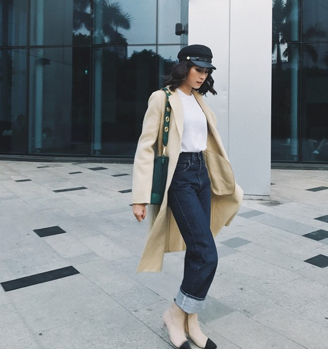 Trưng dụng áo thun và quần jeans, Diệu Ly khéo léo chọn áo khoác dáng dài để giữ ấm, đồng thời tôn phong cách sành điệu nhờ mix mũ newsboy cùng túi đeo có thiết kế độc đáo.