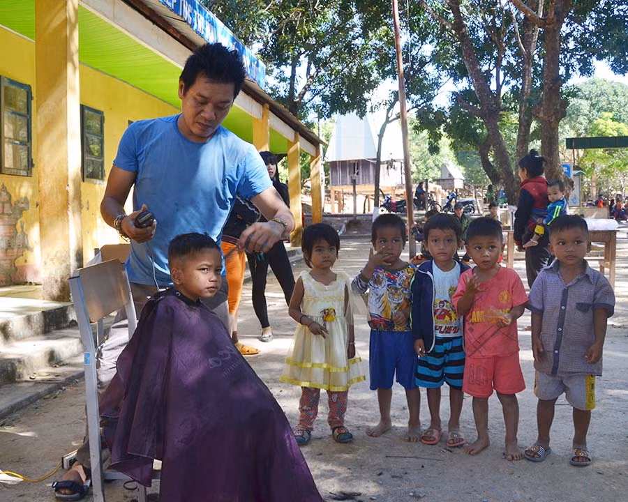 Tình nguyện viên trong Đội cắt tóc cho trẻ em trong làng Dip, xã Ia Kreng. Ảnh: Ngọc Thu
