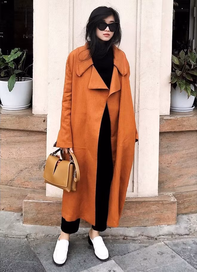 Ngô Thái Bảo Loan cũng ưu tiên những món đồ hơi hướng tối giản trong ngày lạnh. Để ''thắp sáng'' bộ đồ tuyền đen, nhà thiết kế trẻ kết hợp duster coat phủ sắc nâu vàng, mang giày xỏ trắng năng động.