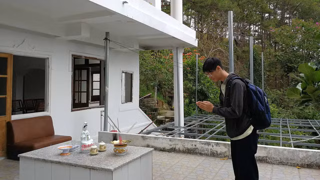 Một du khách thắp nhang tại ngôi nhà ma với thái độ kính cẩn.