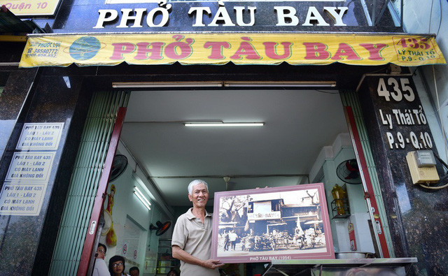 Phở Tàu Bay ngày nay và ông chủ - một trong những hậu duệ của ông Tầu Bay - cùng bức ảnh của tiệm phở này tại Sài Gòn 1954. Phở Tàu Bay ngày nay và ông chủ - một trong những hậu duệ của ông Tầu Bay - cùng bức ảnh của tiệm phở này tại Sài Gòn 1954.