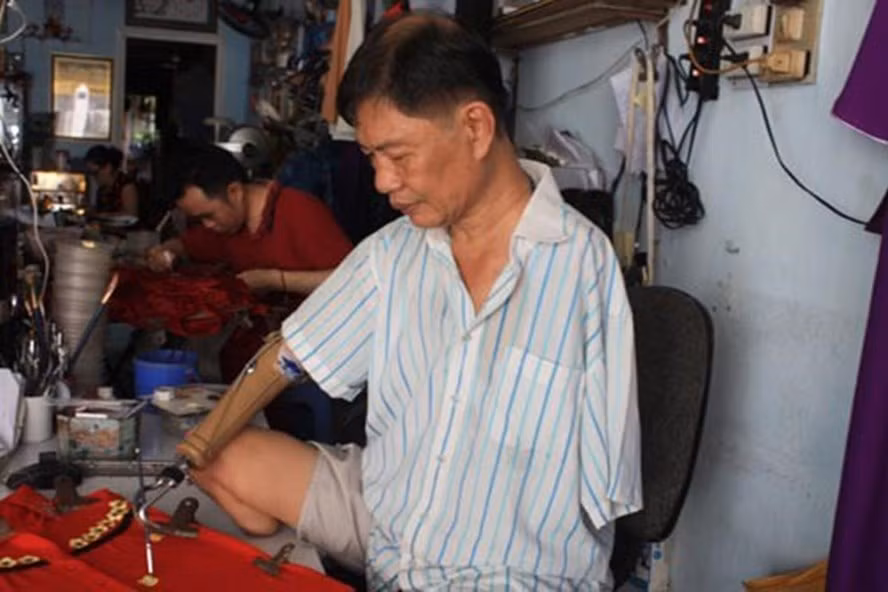 Ông Trần Hùng Bảo miệt mài vẽ hoa trên áo dài thiếu nữ.