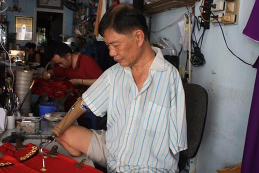 Ông Trần Hùng Bảo miệt mài vẽ hoa trên áo dài thiếu nữ. Ông Trần Hùng Bảo miệt mài vẽ hoa trên áo dài thiếu nữ.