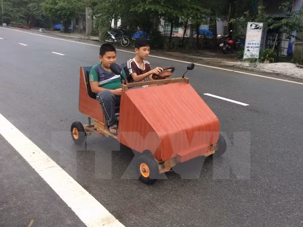 Em Lê Thiên Ân điều khiển chiếc xe ô tô có khung bằng gỗ, chạy bằng nguồn điện ắc quy vừa mới chế tạo.