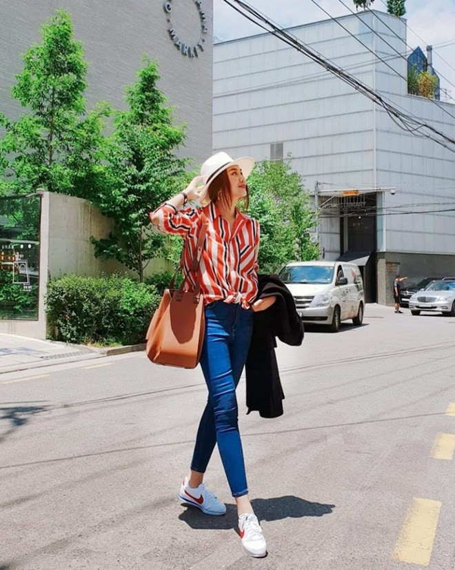  Thanh Hằng khoe dáng nuột nà với quần jeans cạp cao và sơ mi kẻ sọc màu nổi. Đôi giày thể thao cùng mũ cói vành tròn là cặp phụ kiện hoàn hảo, vừa giúp siêu mẫu che nắng lại thoải mái di chuyển khi tản bộ trên những con phố tại Hàn Quốc. Và tất nhiên, chiếc túi Hammock từ Loewe – “bảo bối” yêu thích của người đẹp cũng đồng hành trong chuyến đi này.
