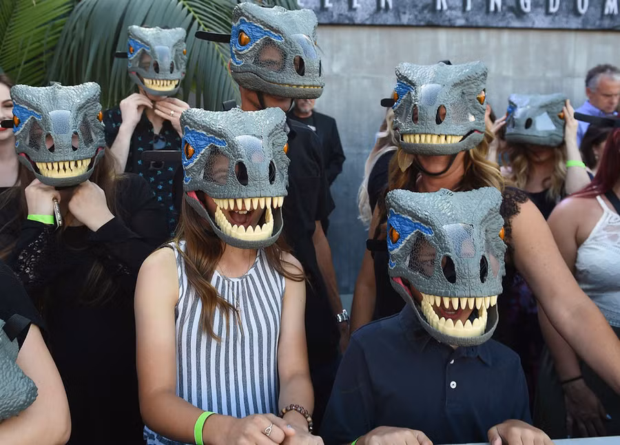Người hâm mộ của loạt phim về thế giới khủng long được phát những mặt nạ khủng long tại The Walt Disney Concert Hall, bang California (Mỹ) - Ảnh: AFP