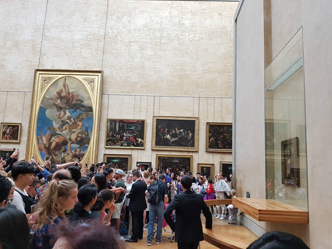 Nhân viên an ninh luôn vất vả ổn định đám đông chen lấn phía trên trước bức tranh 