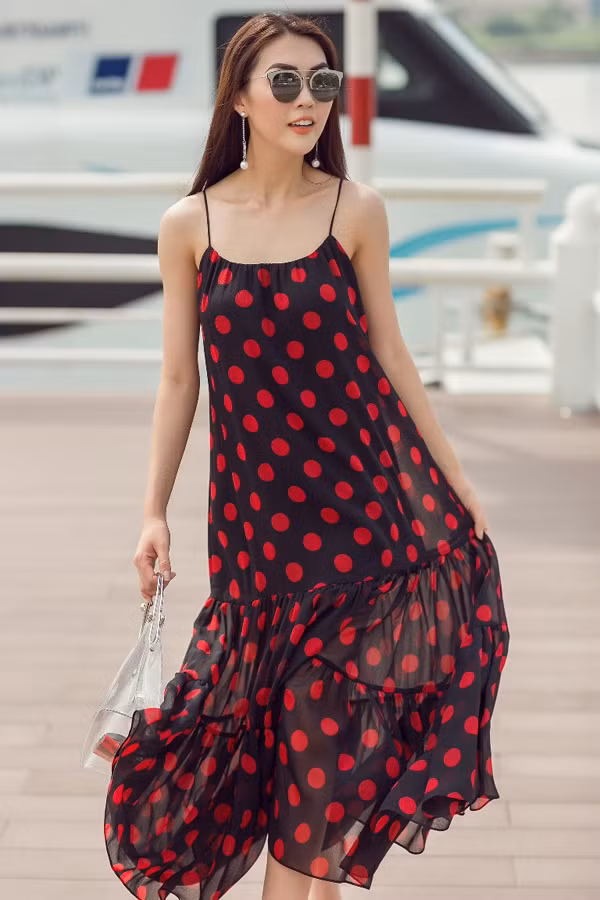  Váy hai dây hạ eo tông đỏ đen bắt mắt được mix cùng các phụ kiện kính mắt, túi xách và hoa tai phù hợp xu hướng.
