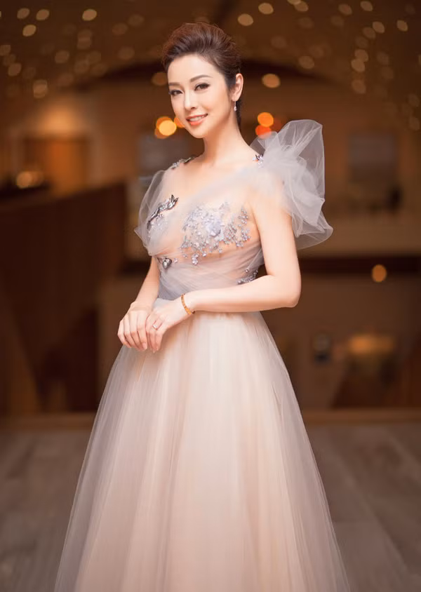 Đến chúc mừng Thuỷ Top mở công ty mới, Jennifer Phạm giúp mình tôn nét yêu kiều trong thiết kế váy dạ hội trong suốt trang trí pha lê và tạo khối vai áo điệu đà.