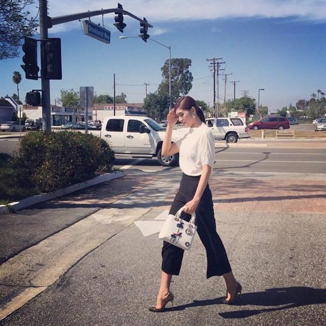Huỳnh Tiên sải bước dưới nắng với bộ đồ đen trắng tôn dáng. Chiếc túi Dior đính kết phụ trang đã giúp cô nàng thêm thanh lịch, tỏa sáng.