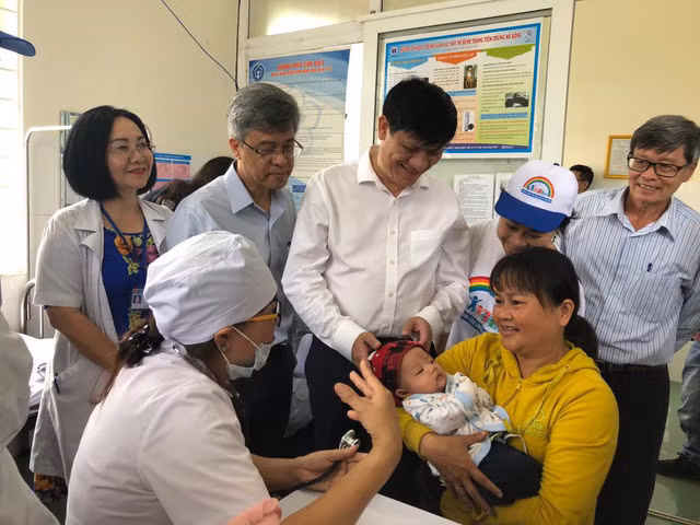 Cán bộ y tế khám sàng lọc, hướng dẫn gia đình chăm sóc trẻ sau tiêm vắc xin.