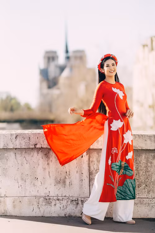 Họa tiết hoa sen trắng và lá sen xanh nổi bật trên tà áo dài đỏ. Mỗi thiết kế được tạo ra đều là quá trình tâm huyết và sáng tạo của NTK, mang đến sự quyến rũ nhưng vẫn kín đáo cho cô dâu Á đông. 