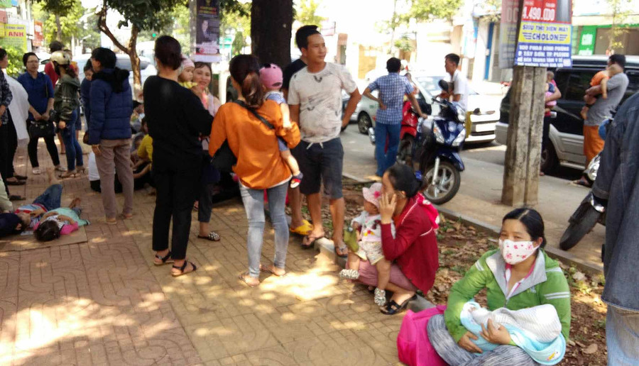 Nhiều phu huynh ngồi trên vỉa hè đường Phan Đình Phùng chờ tiêm phòng cho con. Ảnh: Hà Phương