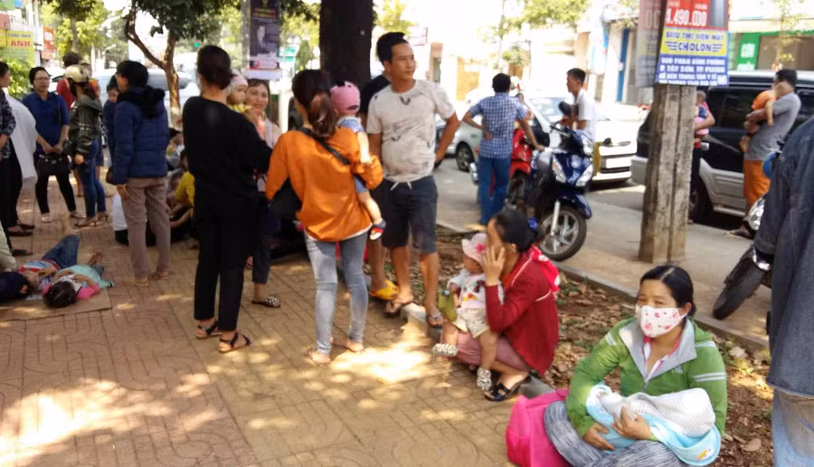Nhiều phu huynh ngồi trên vỉa hè đường Phan Đình Phùng chờ tiêm phòng cho con. Ảnh: Hà Phương