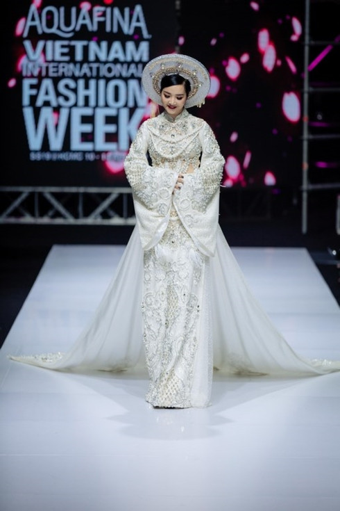 Khoác lên mình trang phục áo dài trắng được đính kết những hột đá, pha lê lấp lánh cộng hưởng phần tà có chiều dài “khủng”,...