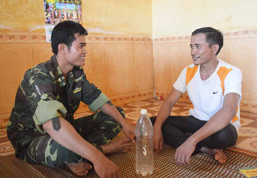  Trưởng thôn Rơ Lan Vân (bìa phải) trò chuyện với Bộ đội Biên phòng. Ảnh: A.H