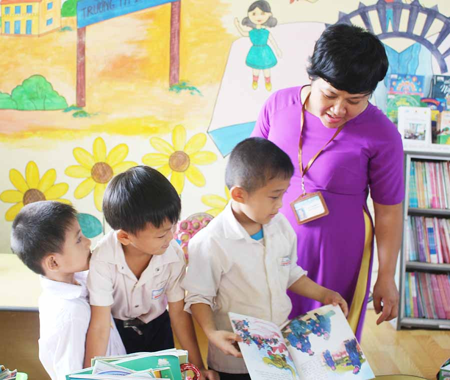  Một em học sinh khuyết tật (thứ 3 từ trái sang) được cô Lê Thị Quỳnh Ly hướng dẫn tận tình trong một buổi đọc sách ở thư viện. Ảnh: N.G