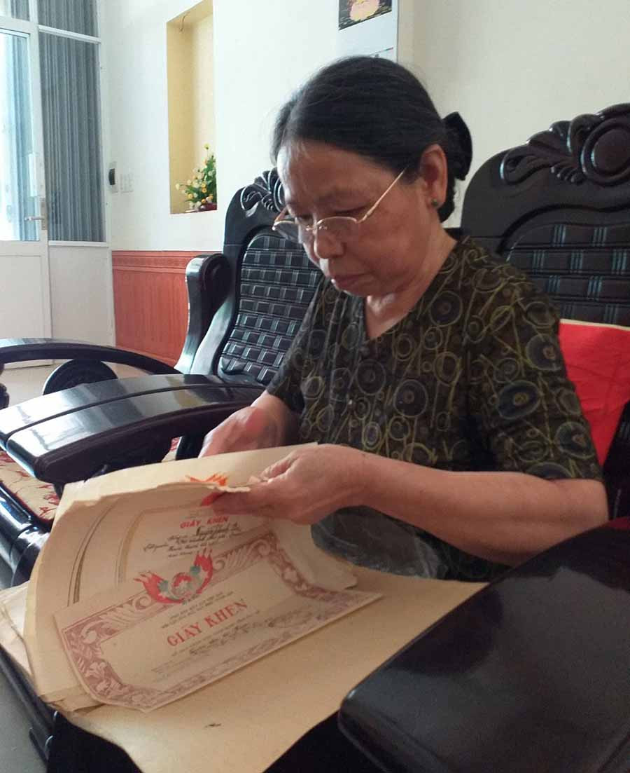  Bà Kim đang lật giở những tấm bằng khen, giấy khen được tặng. Ảnh: P.D