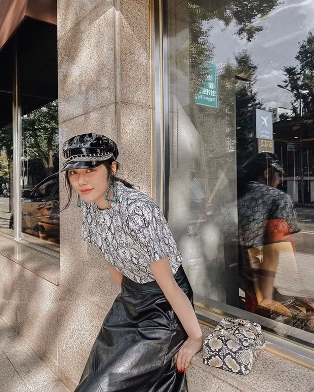 Huỳnh Tiên ghi điểm với combo áo thun họa tiết da trăn với chân váy da, kết hợp túi ăn ý cùng mũ baker boy sành điệu.