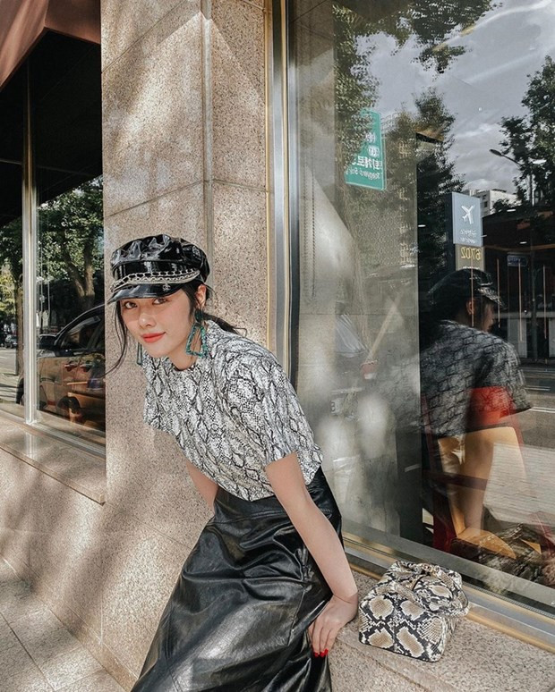 Huỳnh Tiên ghi điểm với combo áo thun họa tiết da trăn với chân váy da, kết hợp túi ăn ý cùng mũ baker boy sành điệu.