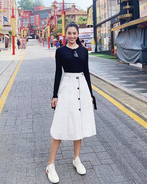  Tiểu Vy tươi tắn trên phố Hàn Quốc trong chuyến du lịch tới xứ củ sâm. Hoa hậu Việt Nam 2018 diện áo thun đen cùng chân váy trắng, mang giày thể thao khỏe khoắn.