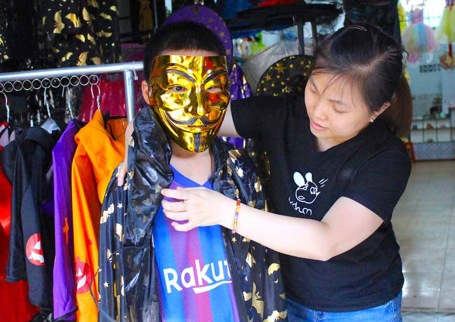 Chị Lý Bội Quân (quản lý G.A.D Shop) giúp khách hàng thử trang phục Halloween. Ảnh: Mộc Trà Chị Lý Bội Quân (quản lý G.A.D Shop) giúp khách hàng thử trang phục Halloween-Ảnh Mộc Trà