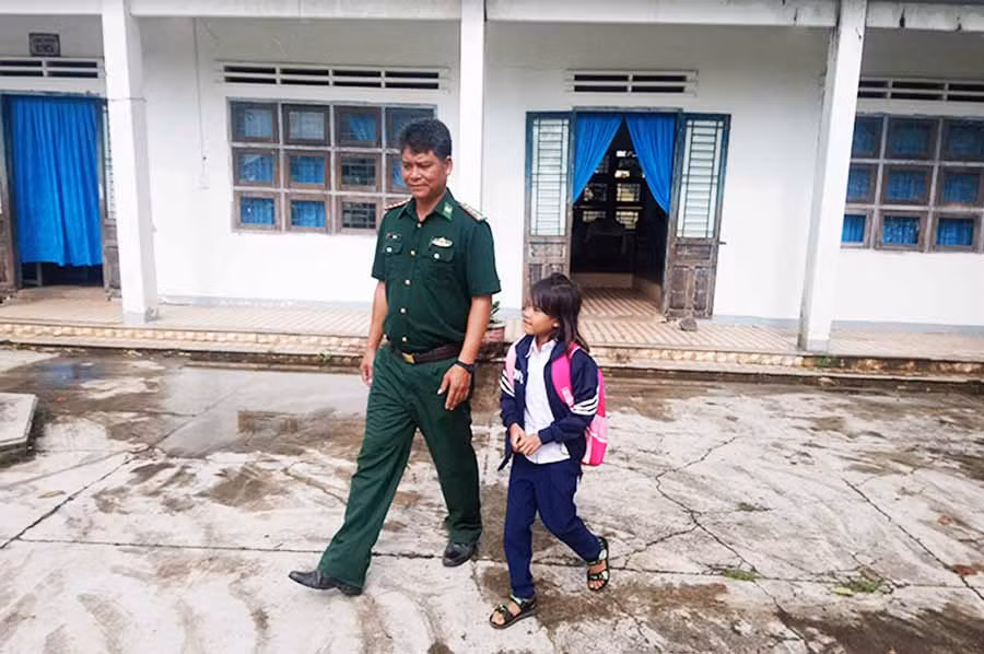  Đại úy Rơ Ô Thuy-Đội trưởng vận động quần chúng Đồn Biên phòng Ia Mơr đưa con nuôi Ksor Nương đến trường. Ảnh: T.K.N
