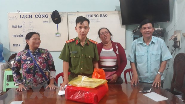 Chị Lê Thị Mai (bên trái) cùng cơ quan chức năng bàn giao số tiền nhặt được cho người đánh mất. (Ảnh: Đậu Tất Thành/TTXVN)