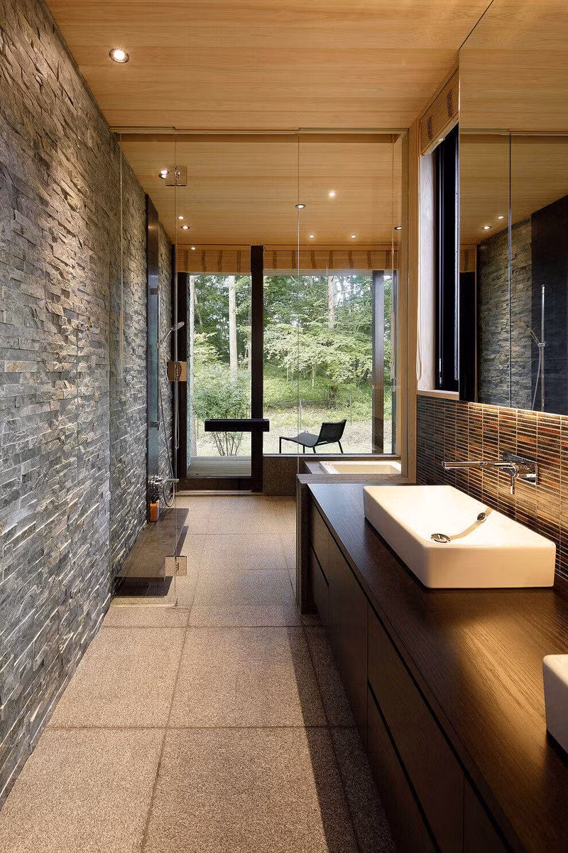 Sàn nhà tắm lát bằng đá nhám, tăng khả năng chống trượt. Một vách ngăn kính ngăn khu tắm ướt và phòng vệ sinh chung.