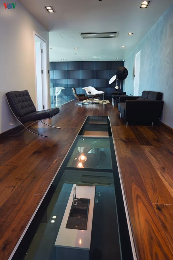 Hành lang ở tầng trên dẫn tới phòng giải trí được làm sàn kính khung thép, có thể nhìn xuyên xuống khu bếp và phòng khách tầng dưới.