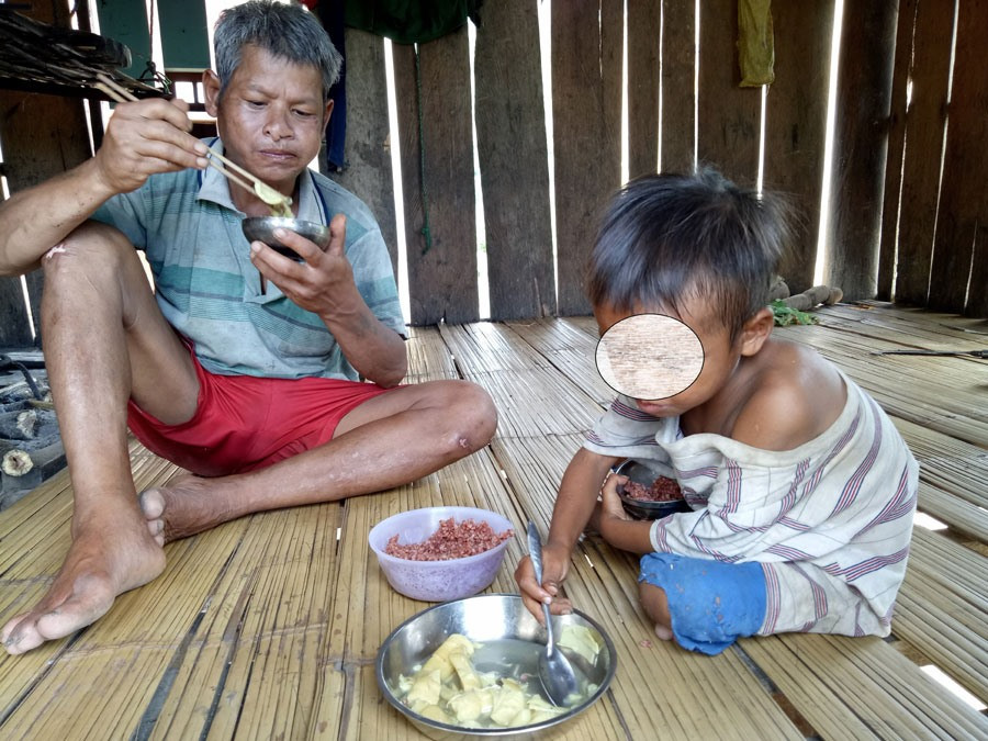 Ông Đinh Văn Nang cùng người con hơn 3 tuổi bên mâm cơm chỉ có măng rừng.