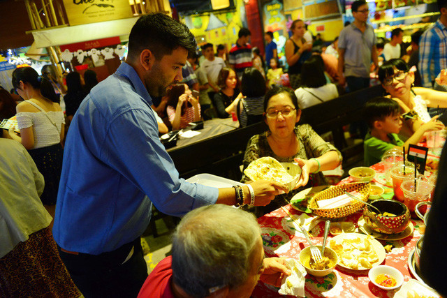 Anh Lokender Singh (Ấn Độ) bưng món ăn truyền thống của Ấn Độ cho thực khách