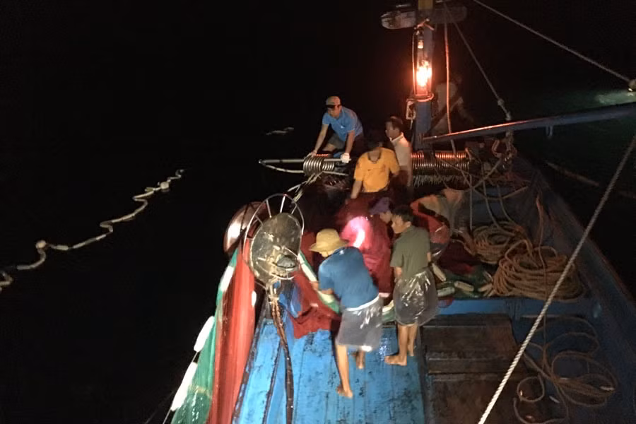 Ngư dân đi bạn trên tàu cá của ông Xếch đang kéo lưới trên biển đêm.