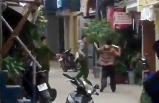 Đối tượng Huy (áo khoác vàng) dùng hung khí tấn công lực lượng công an