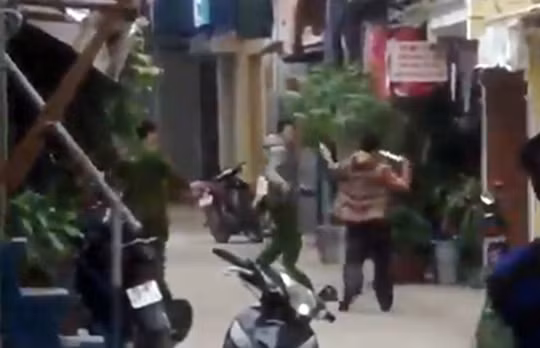 Đối tượng Huy (áo khoác vàng) dùng hung khí tấn công lực lượng công an