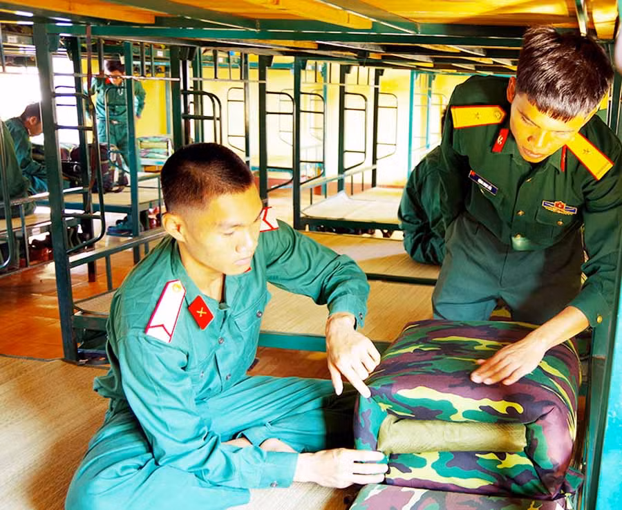  Chiến sĩ mới Lương Sơn Tới đang được cán bộ hướng dẫn gấp chăn. Ảnh: S.T