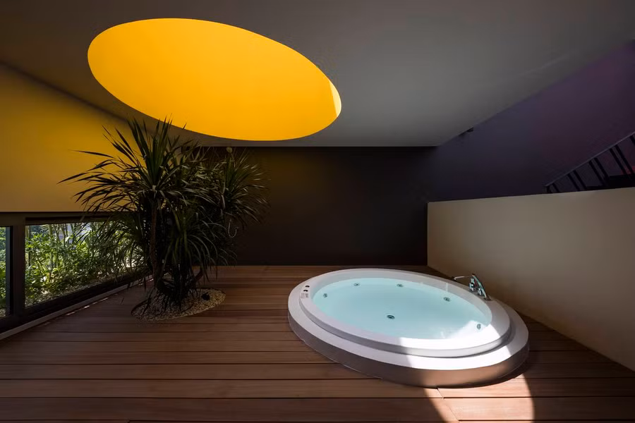 Phòng tắm nằm trong phòng ngủ chính ở tầng hai luôn thông thoáng nhờ cửa sổ hình tròn màu vàng mở ra trên mái (là khu vực ban công ở tầng ba).