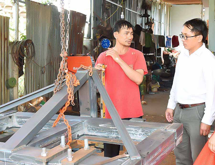  Ông Phạm Văn Tỉnh (bìa trái) giới thiệu về chiếc cày thu hoạch mì. Ảnh: G.H