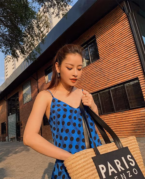 Vẫn là váy hai dây dáng suông nhưng Chi Pu lại chọn họa tiết chấm bi xanh đen để sử dụng. Phụ kiện đi kèm là túi cói đi kèm dây da đen. 
